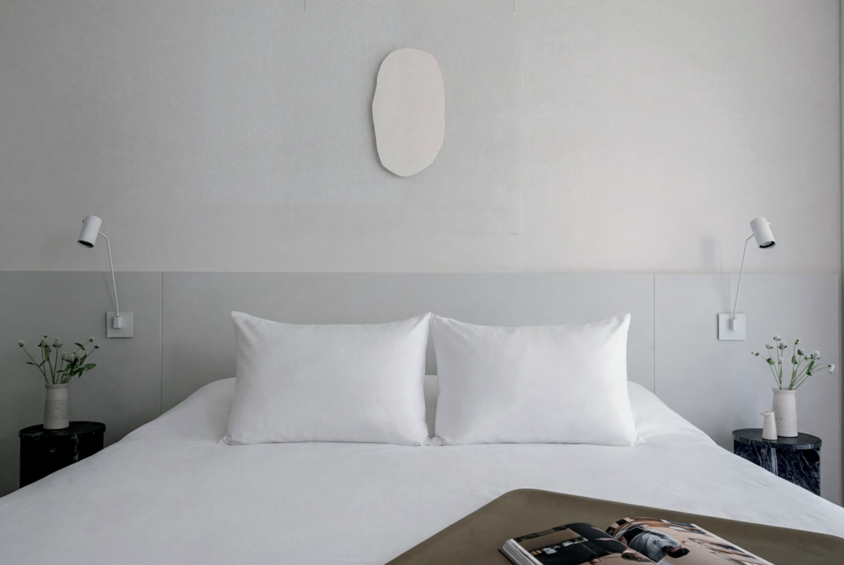 Una obra de Agustina Chapelowicz sobre la pared del dormitorio. Ropa de cama: Hilo.  “Las mesas de luz son de mármol remiggiato, que funcionó como punto de color en la habitación. Si bien la paleta general es muy tranquila, aquí se apostó por el verde, y en el living por el borravino. Estas piezas fueron realizadas junto a nuestro marmolero para Siuk Objetos”.