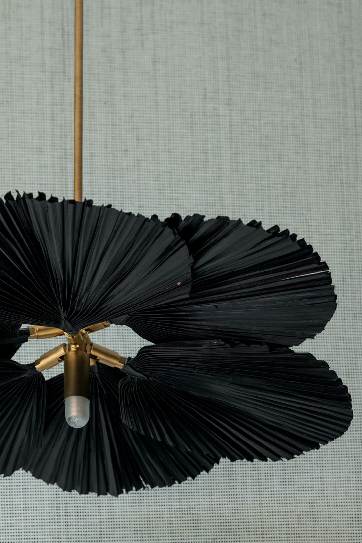 Lámpara negra realizada en fibras naturales, diseñada por Vicky García Baltar y producida por Gloria Rodríguez. La cocina y las alacenas se esconden detrás de sólidas puertas de madera, mientras que las banquetas, diseñadas por la interiorista, suman movimiento y confort al espacio.
